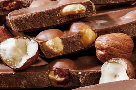 macro  of stack of milk chocolate pieces and hazelnuts