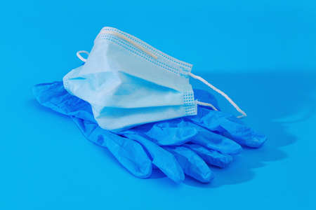 pair of blue medical gloves and medical face mask  on blue background