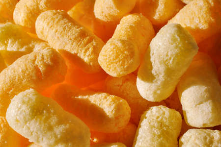 Closeup of puffcorn under sunlight. Sweet snack corn puffs. Macro of puffed corn.の写真素材
