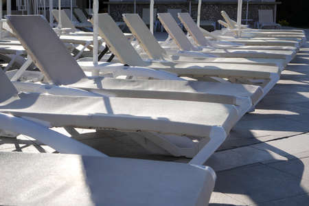 Empty sunbeds by the pool in the morning. Sun beds in a row at poolside in the hotel.の写真素材