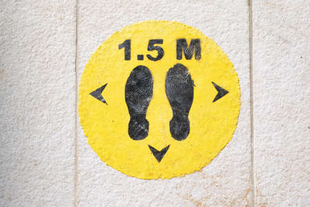 Social distance sign to avoid covid-19. Yellow sign with footprints.