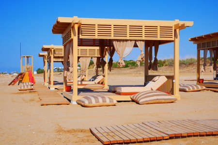 Wooden gazebo on beach with sunbeds and curtains, Empty beach canopies.の写真素材