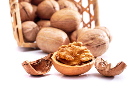 Pile of walnuts in basket and one opened walnut isolated on white backgroundの写真素材
