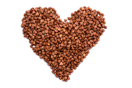 Heart made of buckwheat grains isolated on white backgroundの写真素材