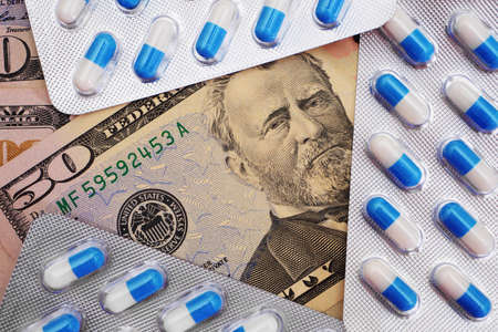Top view on blue and white pills in blister pack on dollar banknotes