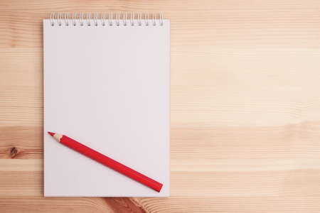 Top view on sketchbook and red pencil on wooden table with copy spaceの写真素材