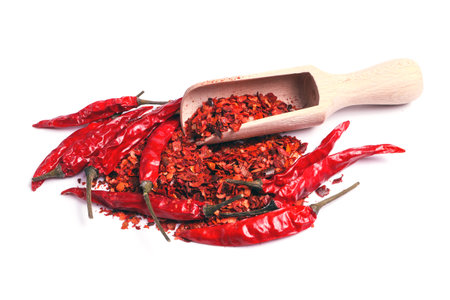 heap of ground dried chili pepper flakes and whole pods with wooden scoop isolated on white backgroundの写真素材