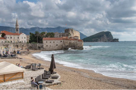 Budva, Montenegro - October 21 2016: tourists on Richard's head beach watching a storm surge hitting against the citadel walls and flooding the beach. The beach is famous after Richard Widmark, who shot a movie in 1963 in the exact same spot located in olのeditorial素材