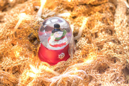 Snowman in snowglobe/snowball on golden, glittery runes with led lights illuminating the scene. Christmas home decoration example.の写真素材