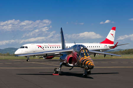 Maribor, Slovenia - April 16, 2016: Red Bull Alpha Jet in front and Austrian Airlines Embraer OE-LWD on apron at Maribor airport. Both came to Maribor for training. Austrian was flying traffic patterns, while the Flaying Bulls had their anual training camのeditorial素材