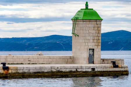 Traditional lighthouse in harbour with green roof on stone pierの写真素材