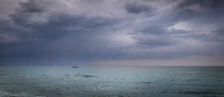 Sailboat in open sea and astorm approaching, dramatic skies, calm seaの写真素材