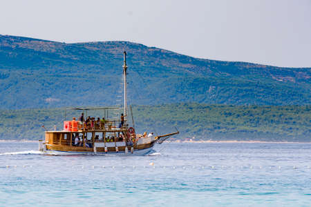 Tourist boat with guests on sightseeing tour between mediterranean island in Adriatic sea, Dalmatia, Croatiaの写真素材