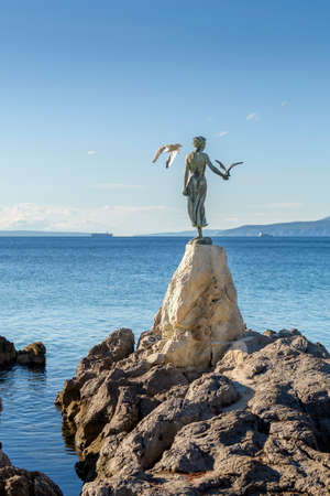 Maiden girl holding a seagull and facing the sea, statue on rocks, Opatija, Croatiaの写真素材