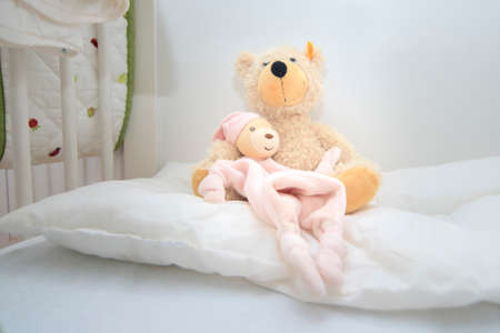Two teddy bears in baby cott sitting on white pillowの写真素材