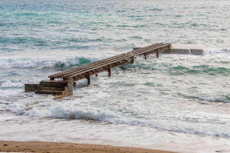 Rusty isolated pier on the background of the sea and wavesの写真素材