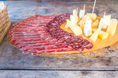 Cold meat plate with cheese on cutting board on wooden backgroundの写真素材
