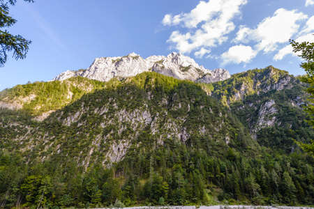 A beutiful landscape in the mountains, clouds above peaks and forest in foregroundの写真素材