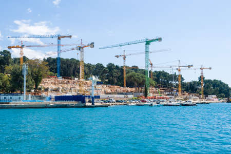 Rovinj, Croatia - April 29, 2017: Construction cranes at the seaside building a new beach resort, hotel at the seaside, construction work, heavy machineryのeditorial素材