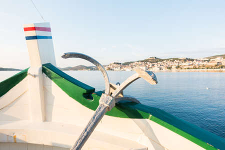 View of boat, ship bow with traditional anchor, mediterranean old historic city in background