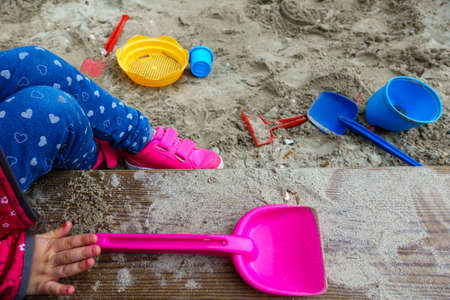 sandbox background children hand holding a pink showelの写真素材