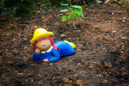 Garden gnome, dwarf on soil, colorful girl as gardenerの写真素材