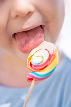 Little kid, child with colorful lolipop, licking on the lolipop, unrecognizableの写真素材