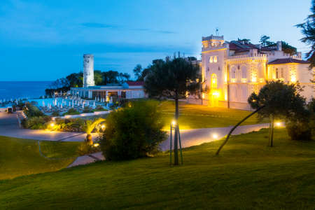 Ancient traditional stone lighthouse in dawn, oldest lighthouse in the Adriatic sea on Sveti Nikola island near Porec, Croatia, next to a luxury appartment villa and swimming pool, tourist resortの写真素材