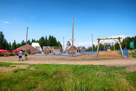 Rogla, Slovenia - Aug 5 2018: Hikers passing by a children playground made of fairytale wooden houses and a small zip line. Rogla is popular with hikers and families for outdoor activities.のeditorial素材