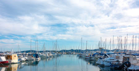 Rows of yachts and sailing boats in marina in the evening, puffy clouds reflected in water, copyspace, harbor in Zadar, Croatiaの写真素材