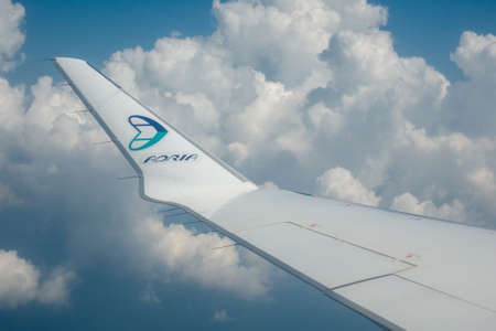 Ljubljana, Slovenia - August 25 2018: View through airplane window on wing of airplane, Adria Airways logo on wing tip, clouds and blue sky backgroundのeditorial素材