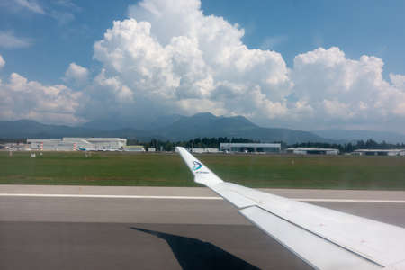Ljubljana, Slovenia - August 25 2018: View through airplane window on wing of airplane, Adria Airways logo on wing tip and Ljubljana Joze Pucnik airportのeditorial素材