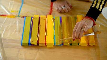 Female artist painting a rainbow with acrylic colors on canvas, hoe made art, DIY tutorial, colorful, painting with gold, tape mask for patternの写真素材