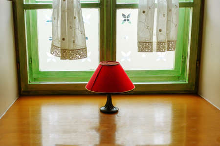 Vintage red lamp with shade on window, intimate indoor scene, reflection in hardwood window shelf, decoration and design conceptの写真素材