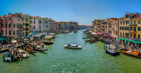 Venice, Italy - April 17 2019: Canale Grande, the Grand Canal in Venice, Italy from the Rialto bridge with gondoals, boats and dense water traffic, tourists walking on shore and sitting in cafesのeditorial素材