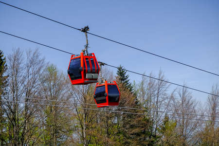 Two red cable cars crossing, overheah cableway on ski slopes and summer adventure park in the european mountains, Pohorje bike park in Maribor, Sloveniaの写真素材