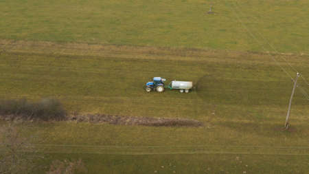 Aerial view of a red tractor and trailer carrying a load of manure on road, agriculture, fertiliying and treating soilの写真素材