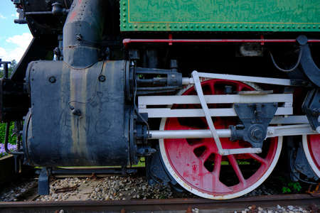 Vintage steam locomotive detail with cranks and red wheels, green bodywork, industrial heritage and...