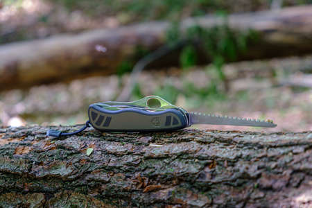 Maribor, Slovenia - May 18 2019: Victorinox Swiss Soldiers Knife Model 08, standard army issue model with extended saw blade on tree trunk in forest, iluustrative editorialのeditorial素材