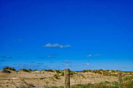 Deep blue sky over the dunes and a fenceの写真素材
