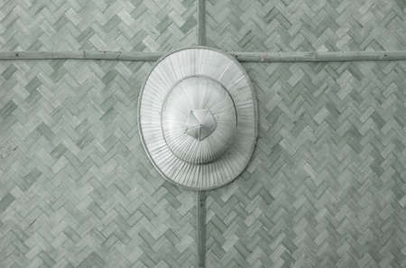 Handmade wooden wicker hat hung on a background pattern woven bamboo.の写真素材
