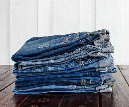 jeans stacked on a wooden backgroundの写真素材