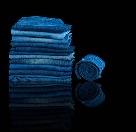 jeans stacked isolated on black background.の写真素材