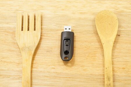 Eat data - usb flash drive on the wood background with spoon and fork.の写真素材