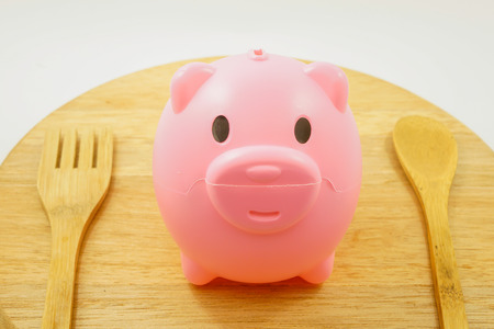 Eat a piggybank on wood background and white background.の写真素材