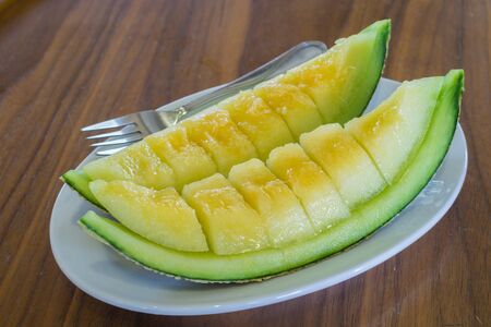 Cantaloupe melon slices on wooden table.の写真素材