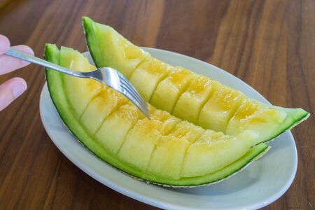 Cantaloupe melon slices on wooden table.の写真素材