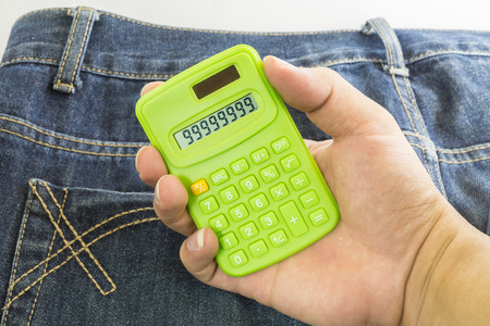 hand holding a calculator on jean texture background ,focus on calculatorの写真素材