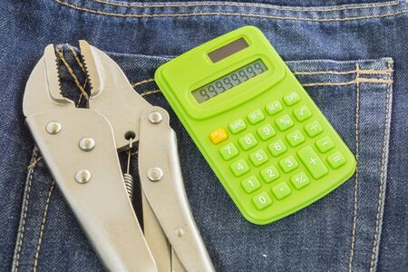 Holding Tools and Calculators on jeans backgroundの写真素材