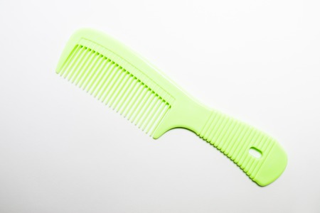 Green plastic comb on a white background.の写真素材